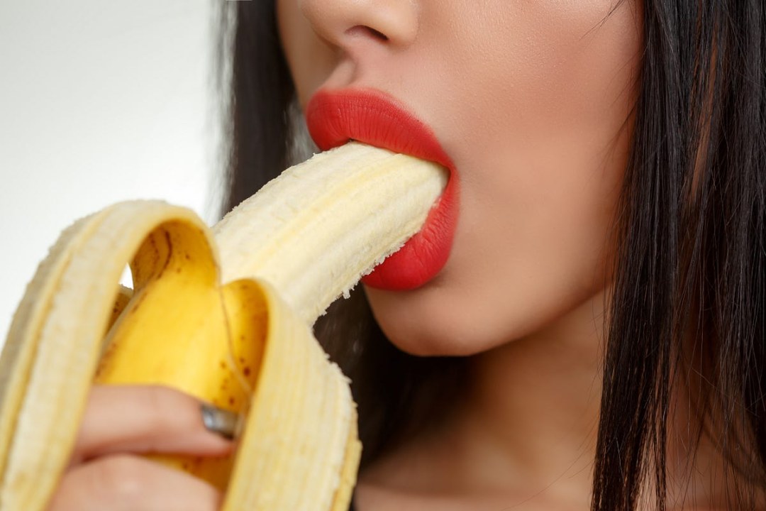 Chica con un plátano en la boca