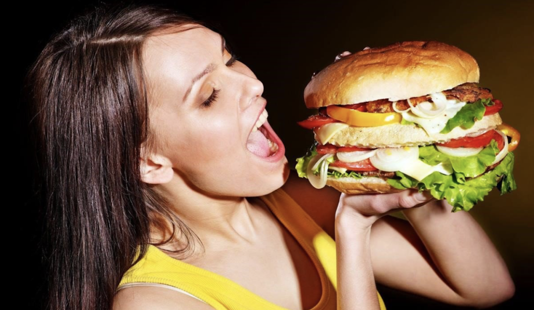 La niña come una hamburguesa