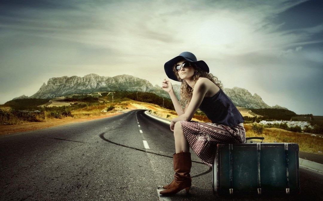 Chica con una maleta en la carretera