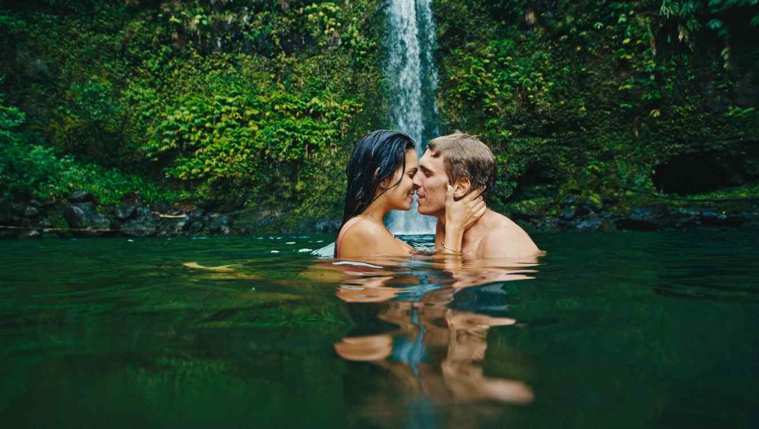 Pareja erótica besándose cerca de la cascada viajando