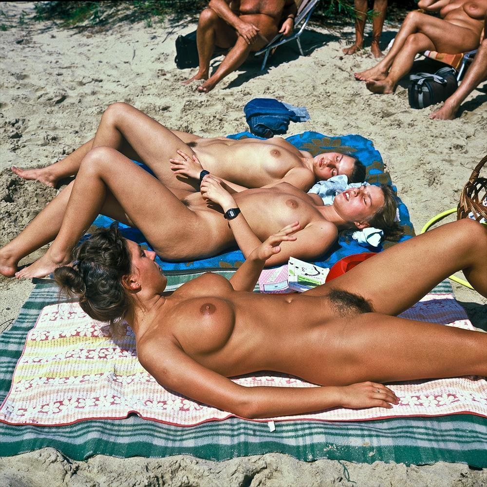 Nudistas desnudos en la playa retro