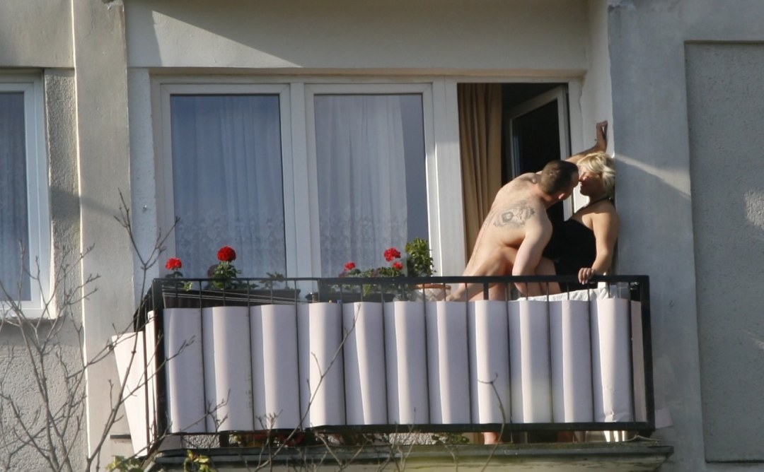 Tomando el sol en el balcón desnudo
