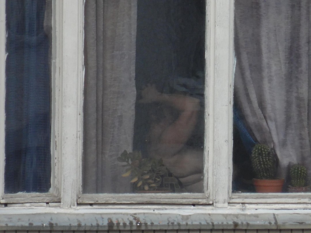 Vecino desnudo en la ventana opuesto