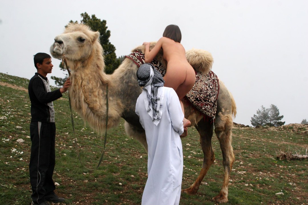 Desnudo con un camello en el desierto
