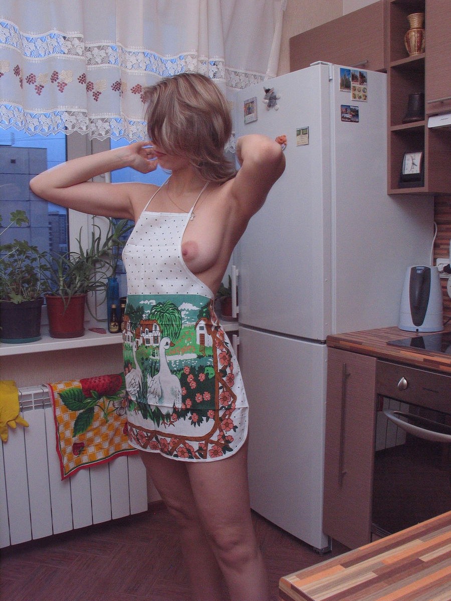 Desnudo en el delantal en la cocina casero