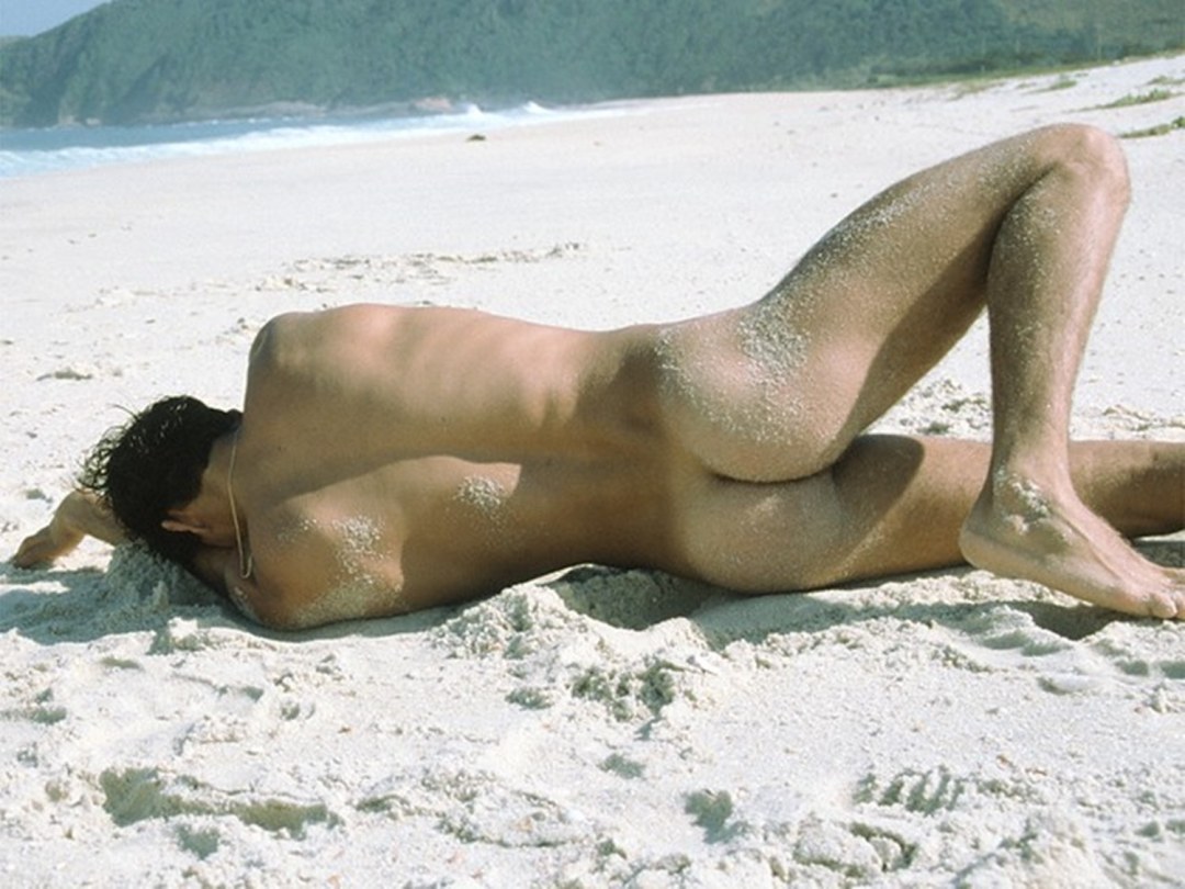 Un chico desnudo yace en la playa