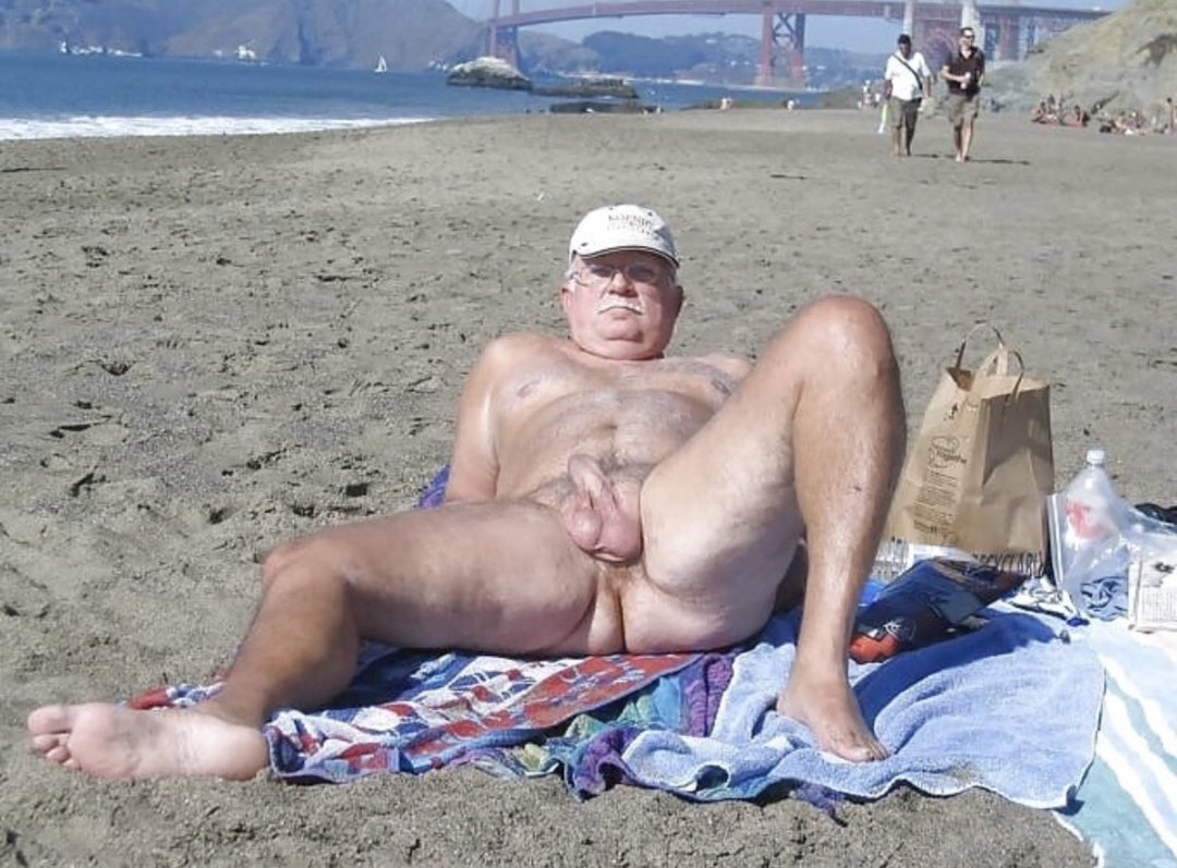 Viejo desnudo en la playa con un pene