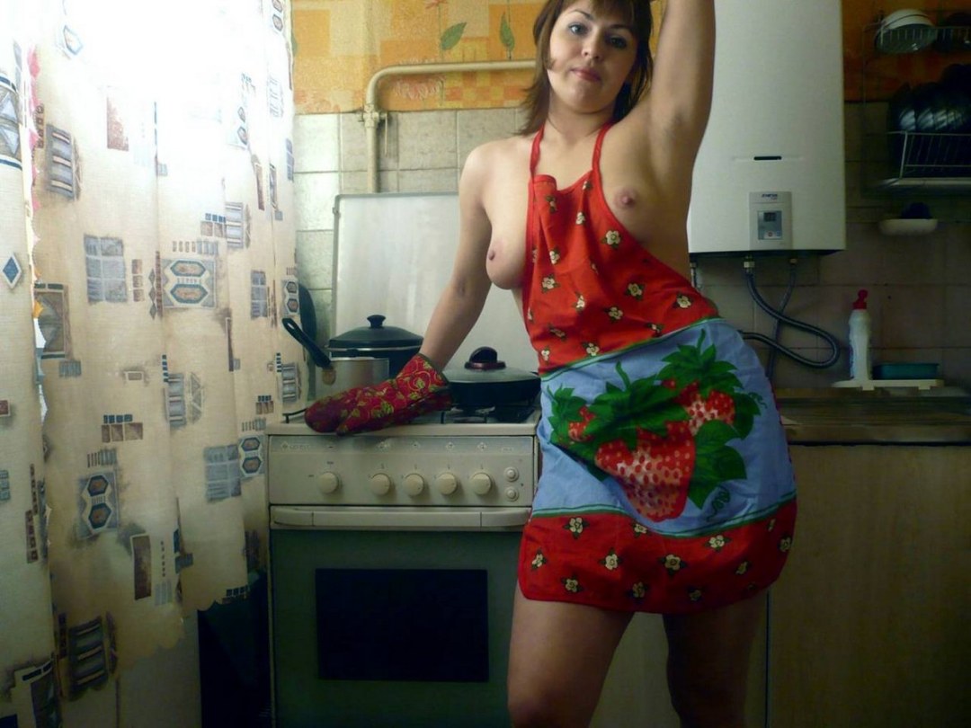 Desnudo en el delantal en la cocina privado